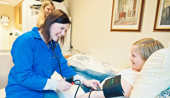 Helselever som demonstrer sjekk av puls på pasient - Klikk for stort bilde